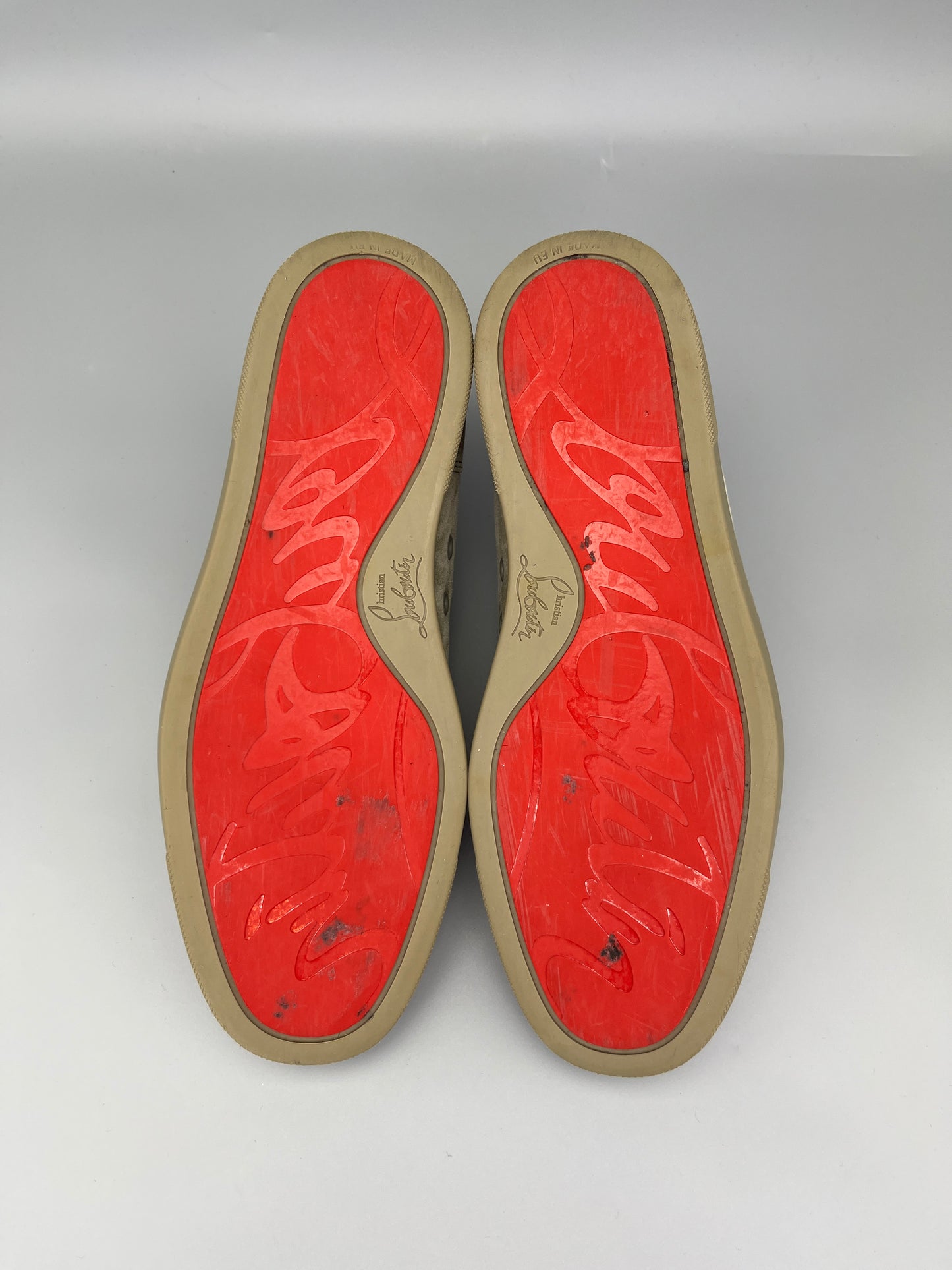 Red soles of shoes with a brand logo on a grey background