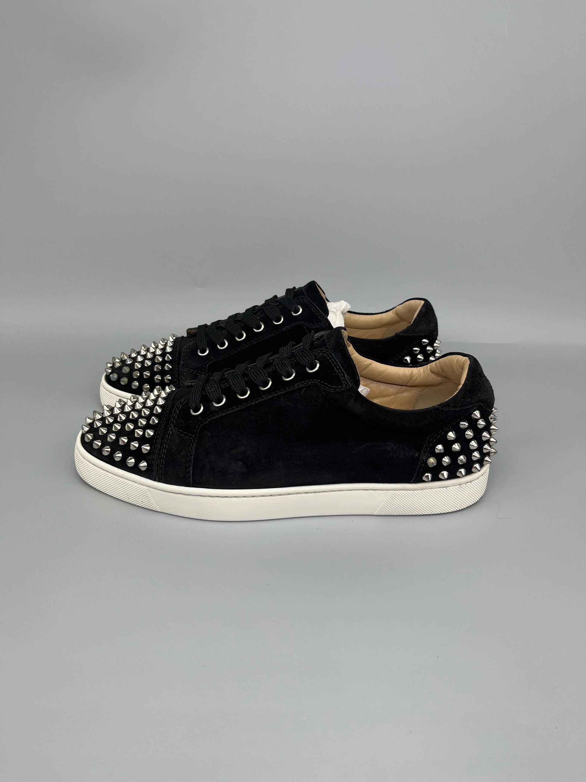 Black studded sneakers on a gray background