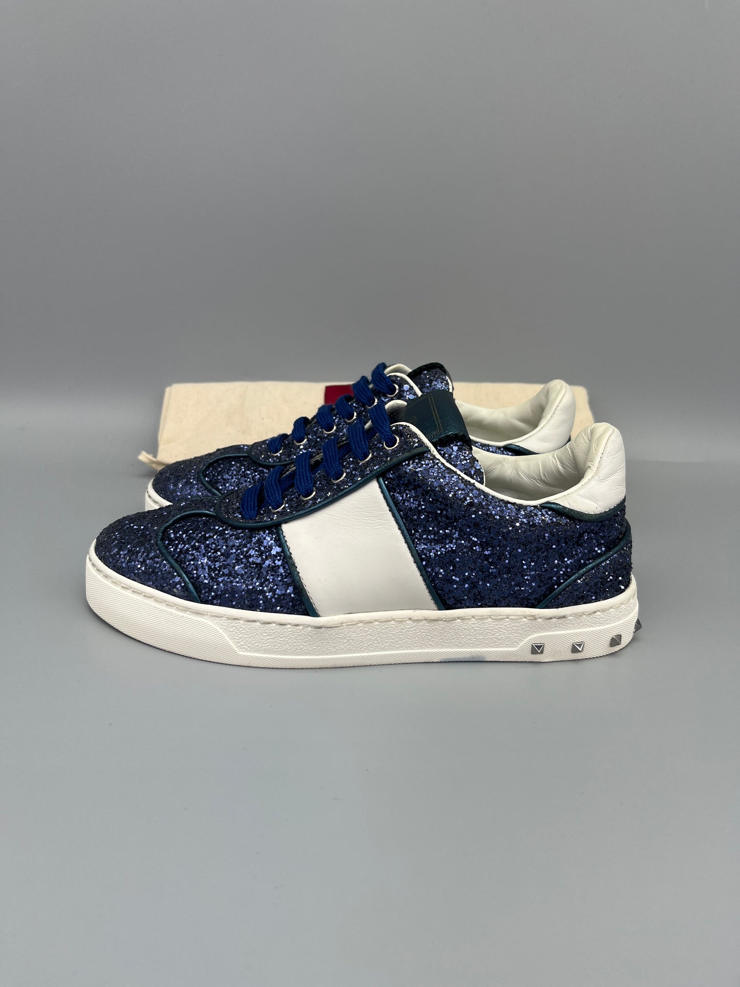 Pair of blue and white glittery sneakers on a gray background
